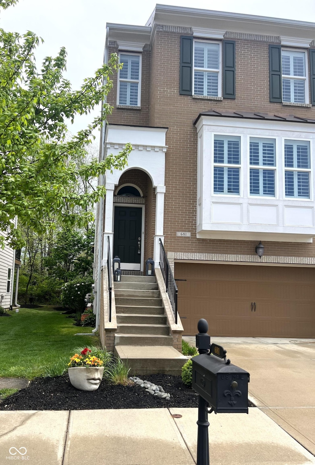 view of front of property with concrete driveway, brick siding, a front yard, and a garage