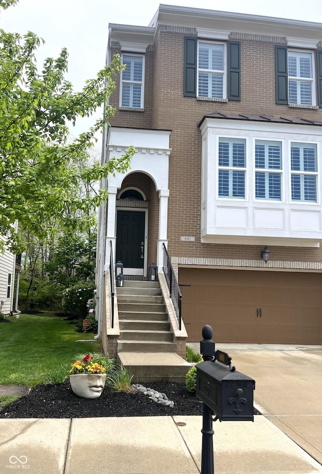 view of front of property with concrete driveway, brick siding, a front yard, and a garage
