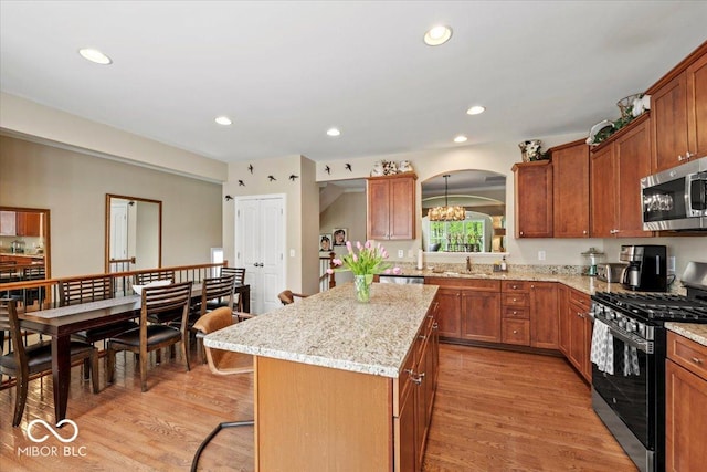 681 Greenford Trl N, Carmel, IN 46032 - kitchen with appliances with stainless steel finishes, a kitchen island, brown cabinetry, light wood-type flooring, and arched walkways