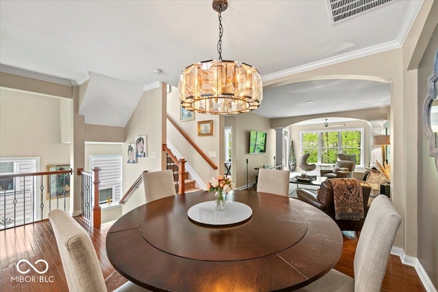 681 Greenford Trl N, Carmel, IN 46032 - dining room with wood finished floors, arched walkways, a chandelier, crown molding, and stairway