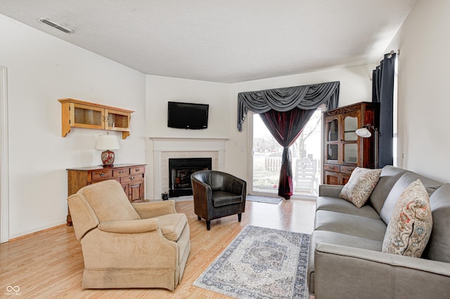 living room with baseboards, a fireplace, visible vents, and light wood-type flooring