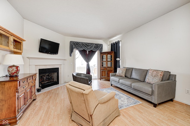 living room with light wood-style floors and a tile fireplace