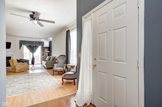 foyer entrance featuring a wealth of natural light, a fireplace, a textured ceiling, and wood finished floors