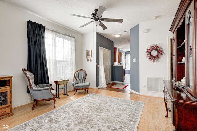 sitting room with plenty of natural light, visible vents, light wood finished floors, and a textured ceiling