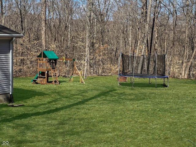 view of yard featuring a trampoline, a wooded view, and a playground