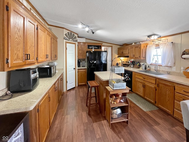 kitchen featuring black appliances, dark wood-type flooring, lofted ceiling, a textured ceiling, and a sink