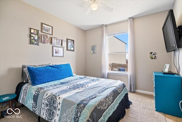 bedroom featuring baseboards, a textured ceiling, light carpet, and ceiling fan