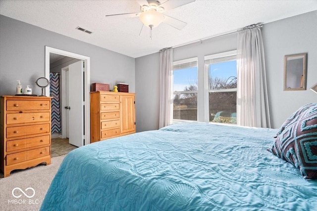 bedroom featuring carpet flooring, a ceiling fan, visible vents, and a textured ceiling