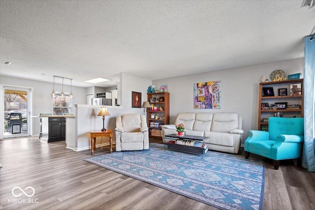 living room featuring a textured ceiling, baseboards, and wood finished floors