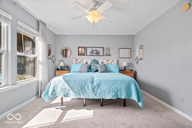 carpeted bedroom featuring baseboards, a textured ceiling, and a ceiling fan