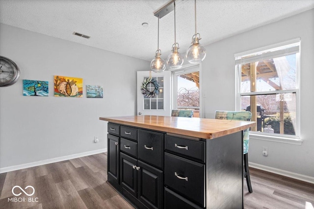 kitchen with visible vents, dark wood-style floors, dark cabinetry, wooden counters, and a healthy amount of sunlight