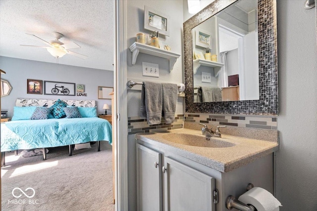 ensuite bathroom featuring vanity, a ceiling fan, ensuite bathroom, a textured ceiling, and tasteful backsplash