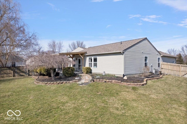 rear view of property featuring a lawn, cooling unit, and fence