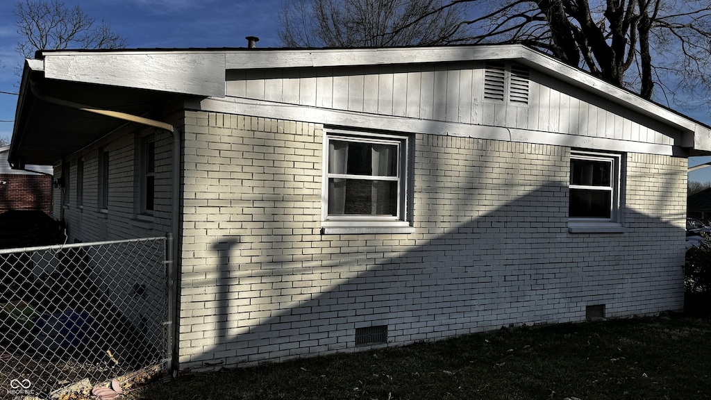 view of side of property featuring fence, brick siding, and crawl space