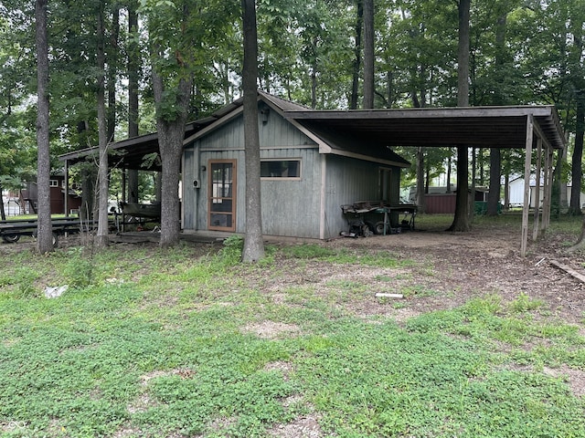 view of outdoor structure with driveway, an attached carport, and an outdoor structure