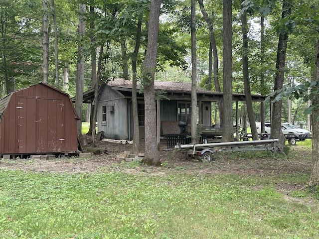 exterior space with an outbuilding, metal roof, a front yard, and a shed