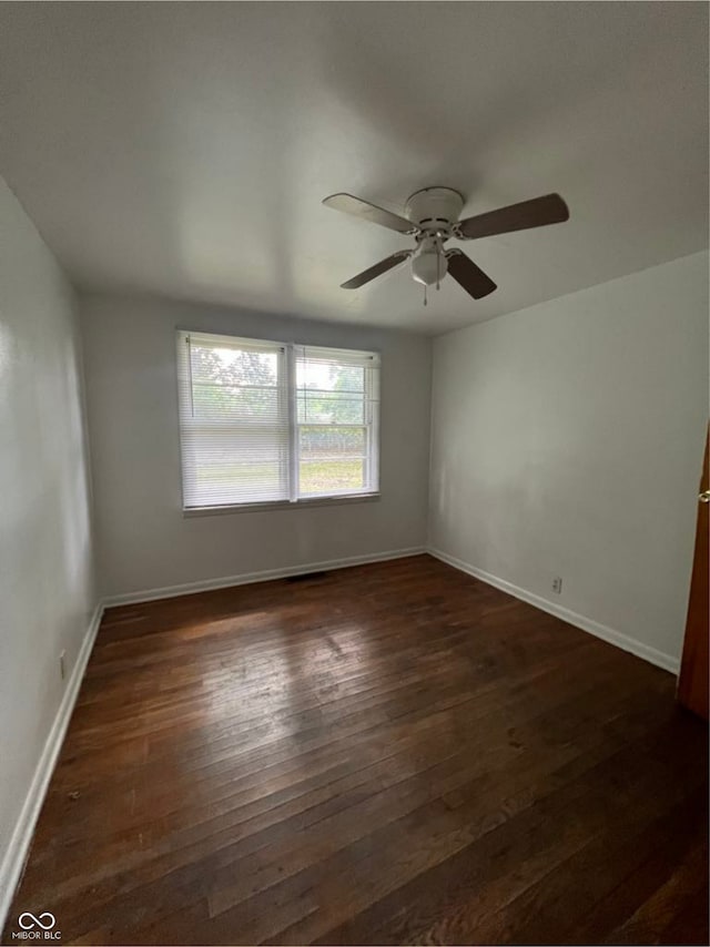 empty room with dark wood-style floors, ceiling fan, and baseboards