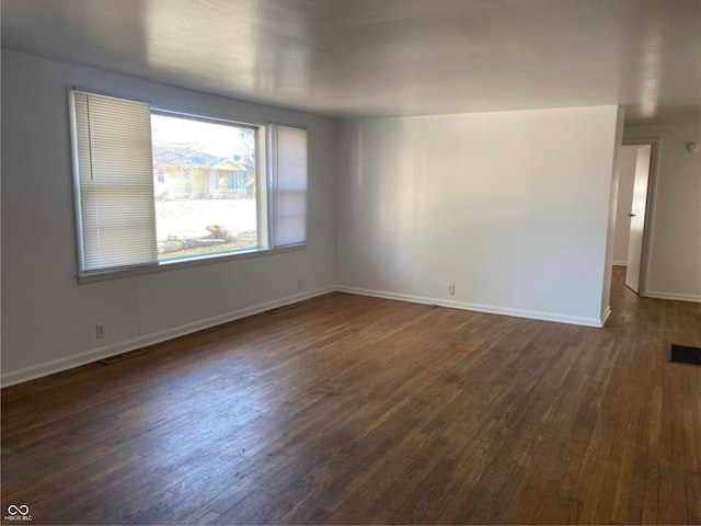 spare room featuring dark wood-style floors, visible vents, and baseboards