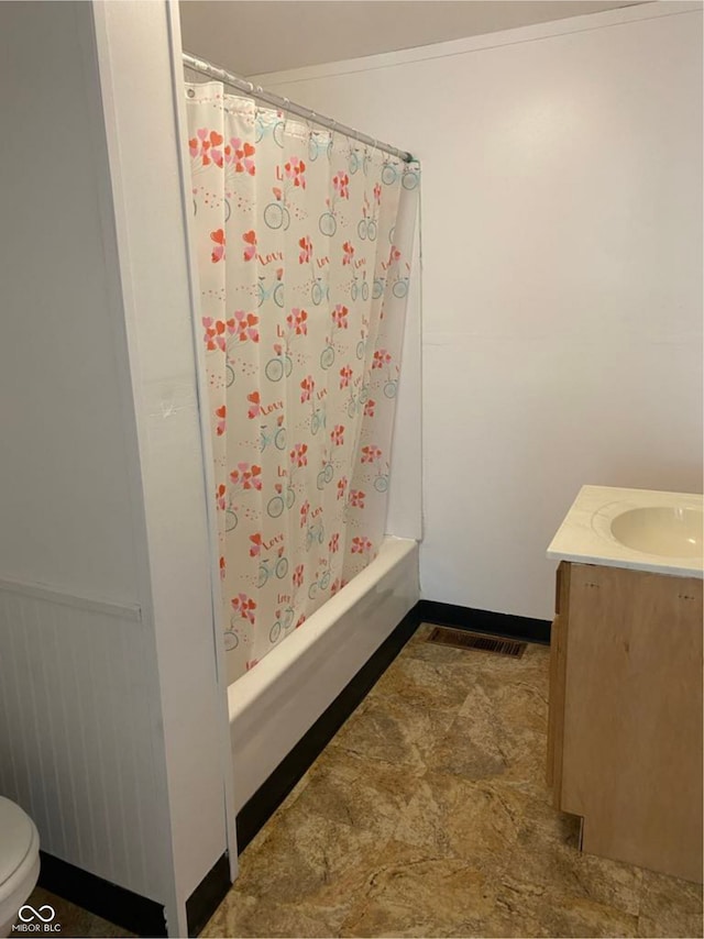 bathroom with vanity, wainscoting, shower / bath combo with shower curtain, and toilet