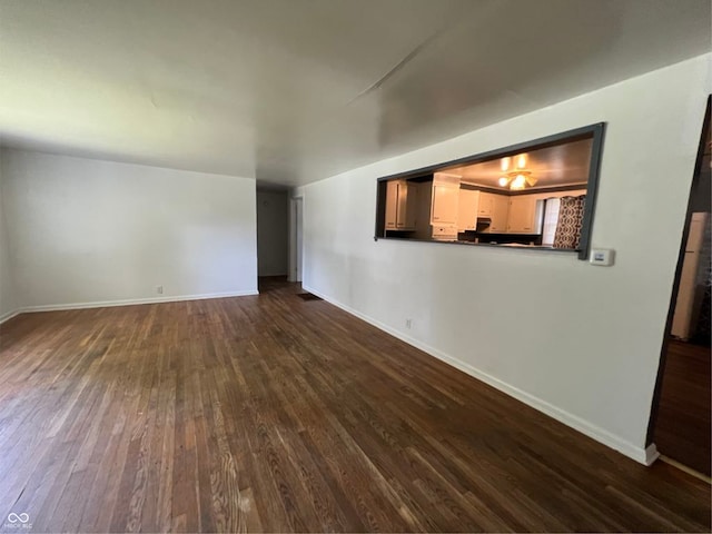 unfurnished room featuring dark wood-style flooring and baseboards