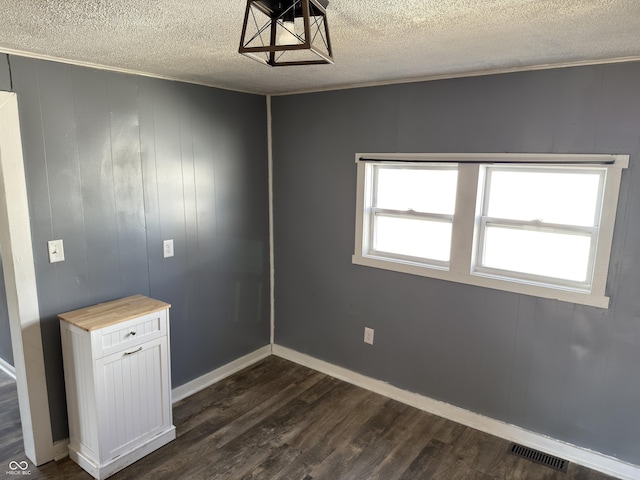 unfurnished room with dark wood-style floors, visible vents, a textured ceiling, and baseboards