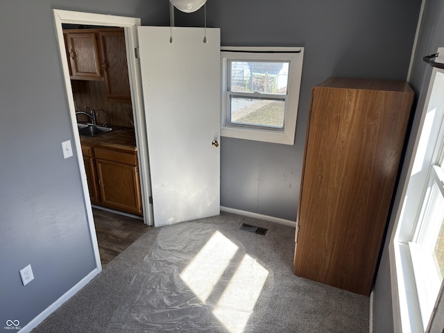 unfurnished bedroom featuring baseboards, carpet, visible vents, and a sink