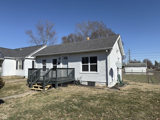 back of house featuring a deck, roof with shingles, a lawn, and fence