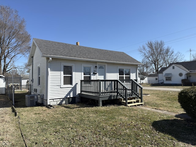 bungalow with cooling unit, a shingled roof, fence, a wooden deck, and a front yard