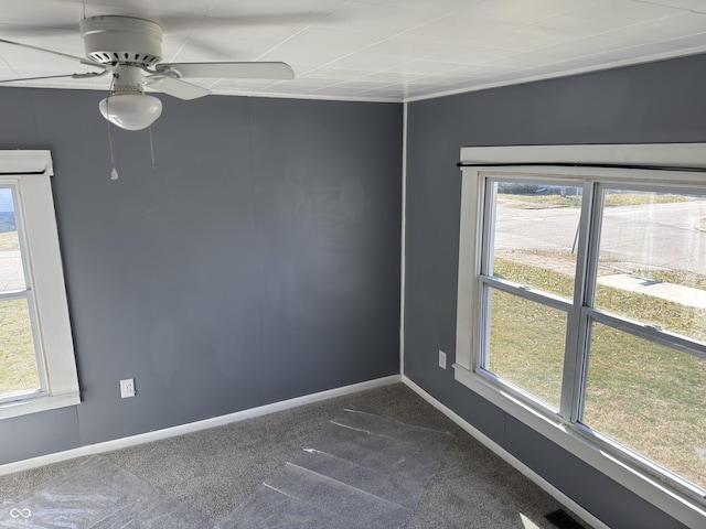 spare room featuring visible vents, dark carpet, baseboards, and ceiling fan