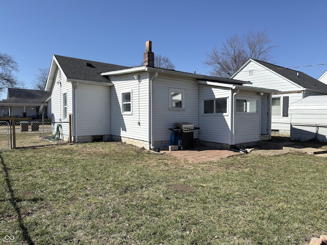 rear view of property featuring a shingled roof, fence, a chimney, and a lawn