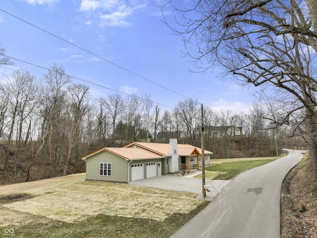 view of property exterior featuring a garage, a yard, driveway, and a chimney