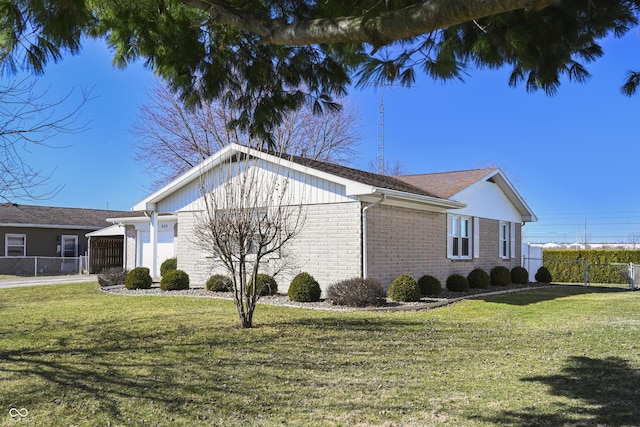 view of side of home with brick siding, a lawn, a garage, and fence