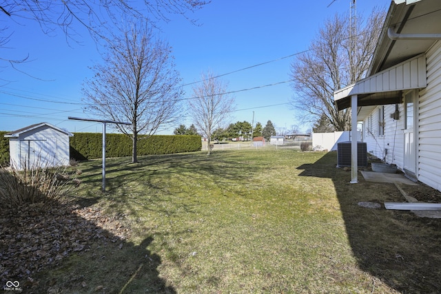 view of yard with a storage unit, an outbuilding, cooling unit, and fence