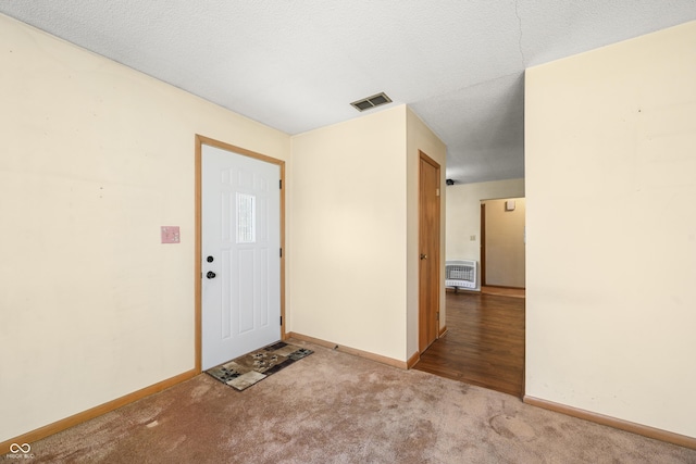 carpeted foyer with visible vents, baseboards, and a textured ceiling