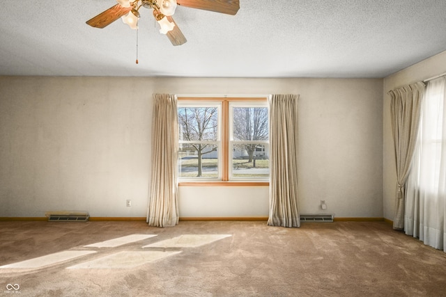 empty room with visible vents, a healthy amount of sunlight, a textured ceiling, and carpet