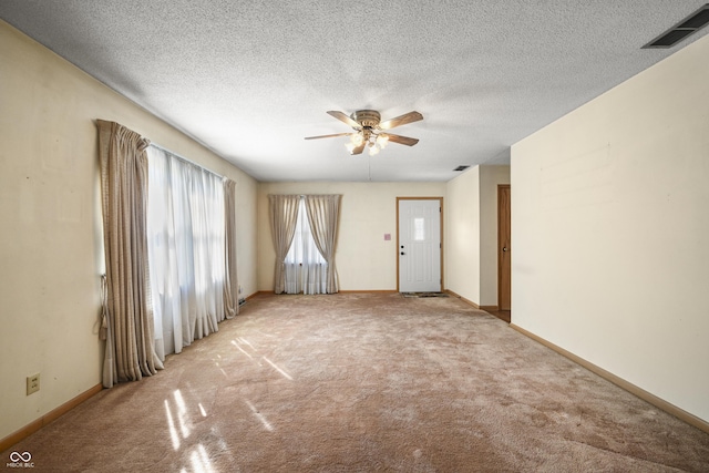 spare room with light carpet, visible vents, baseboards, and a ceiling fan