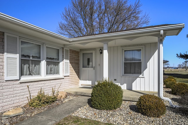 view of exterior entry with a porch and board and batten siding