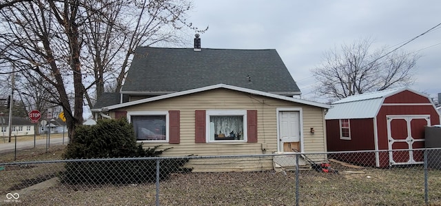 view of front of home with a storage unit, a fenced front yard, and a gambrel roof