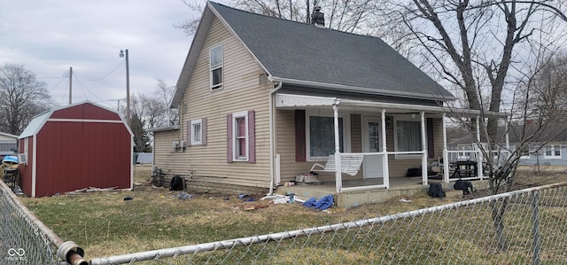 view of front of property with a shingled roof, fence private yard, covered porch, and an outdoor structure