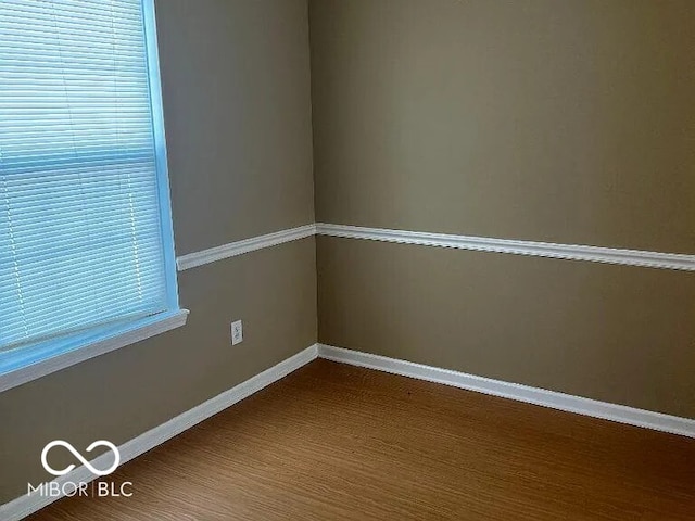 spare room featuring baseboards and wood finished floors