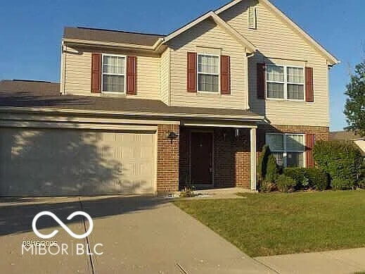 view of front facade featuring a garage, driveway, brick siding, and a front lawn