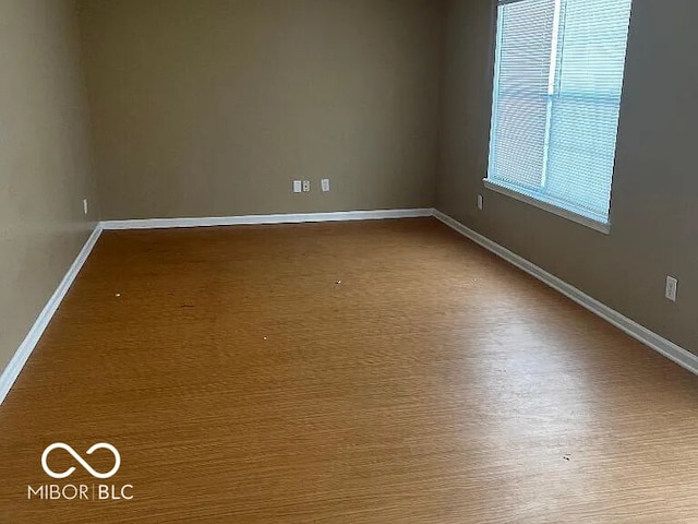 unfurnished room with baseboards and wood finished floors