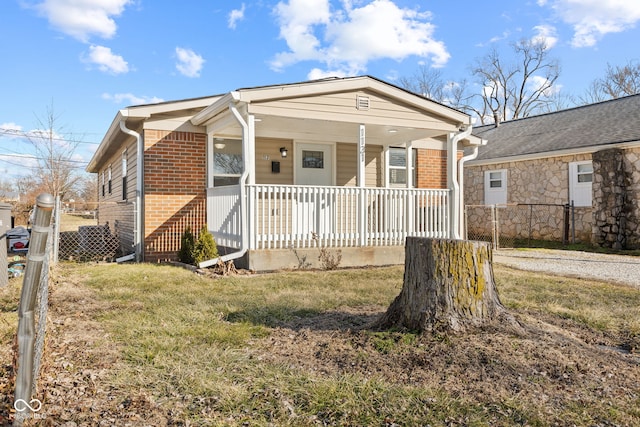 bungalow with a porch, a front lawn, fence, and brick siding