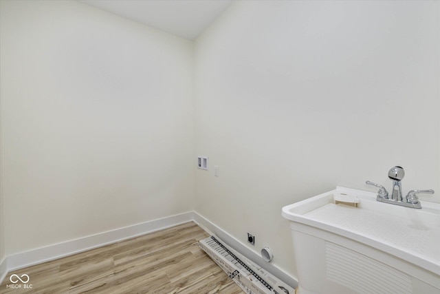 washroom featuring baseboards, laundry area, light wood-style flooring, electric dryer hookup, and a sink