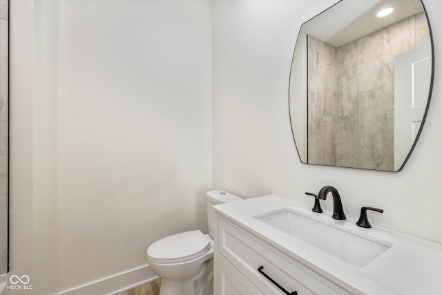 bathroom with baseboards, toilet, and vanity