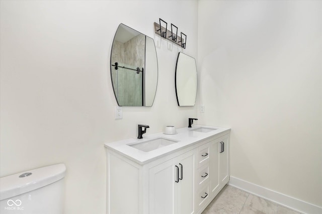 full bath featuring double vanity, toilet, baseboards, and a sink