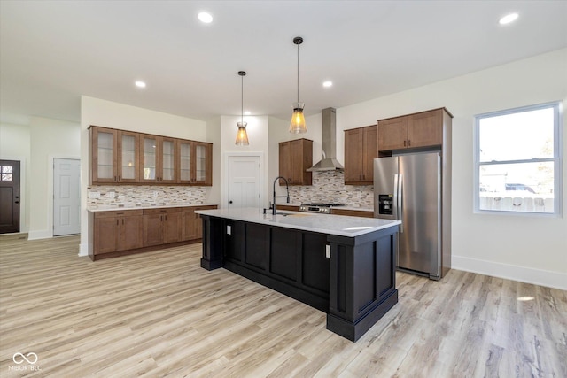 kitchen with wall chimney range hood, stainless steel fridge with ice dispenser, light countertops, range, and a sink