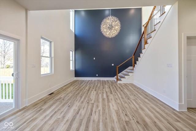 entrance foyer with stairway, baseboards, a towering ceiling, and wood finished floors