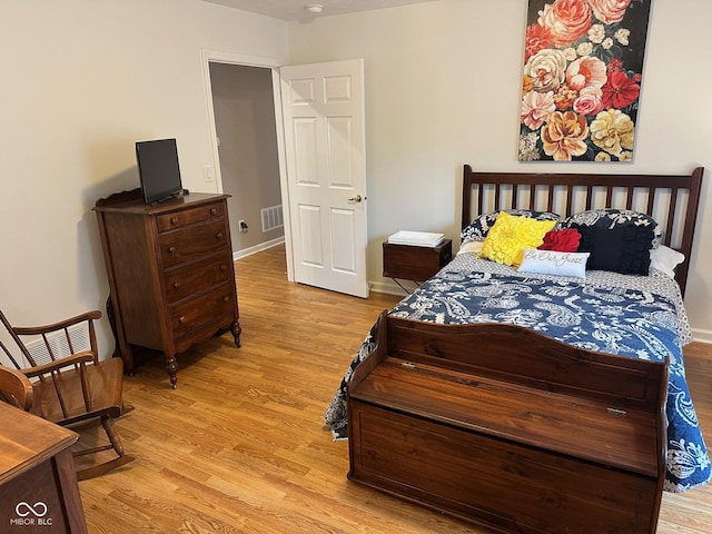 bedroom featuring visible vents, baseboards, and wood finished floors