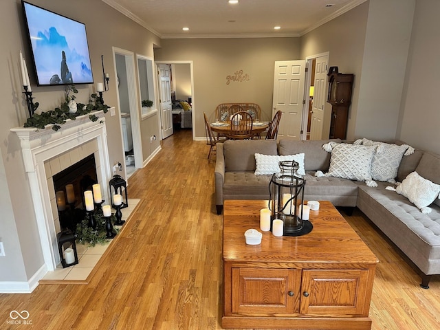 living area featuring crown molding, baseboards, light wood finished floors, and a tile fireplace